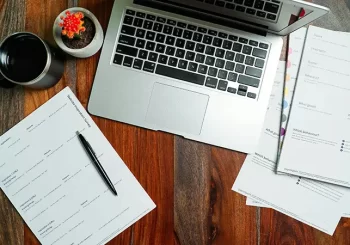 Photo of desk with papers and a laptop